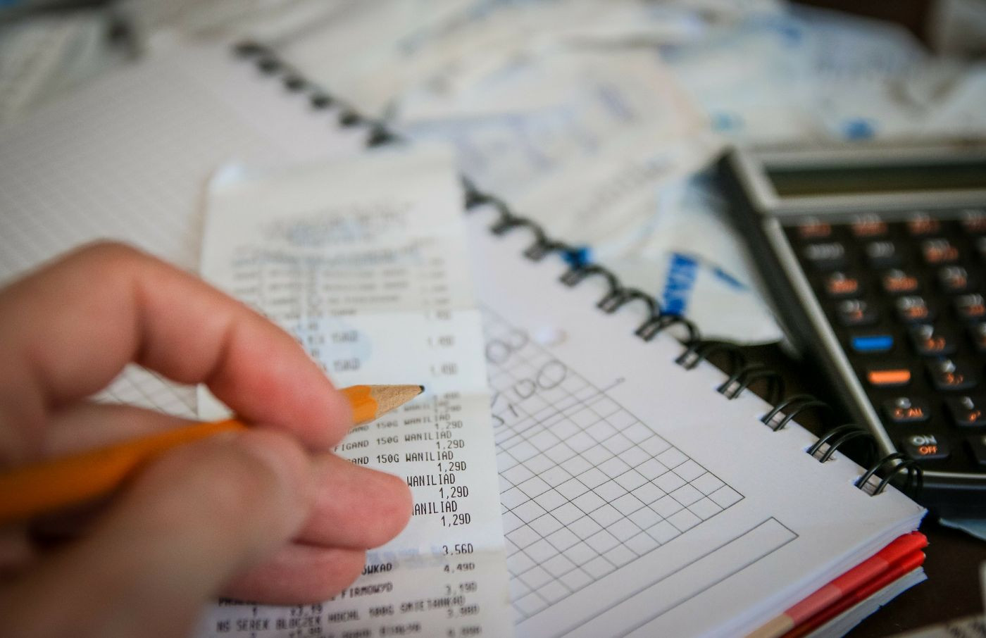 Hand mit Stift über Kontoauszügen und Taschenrechner